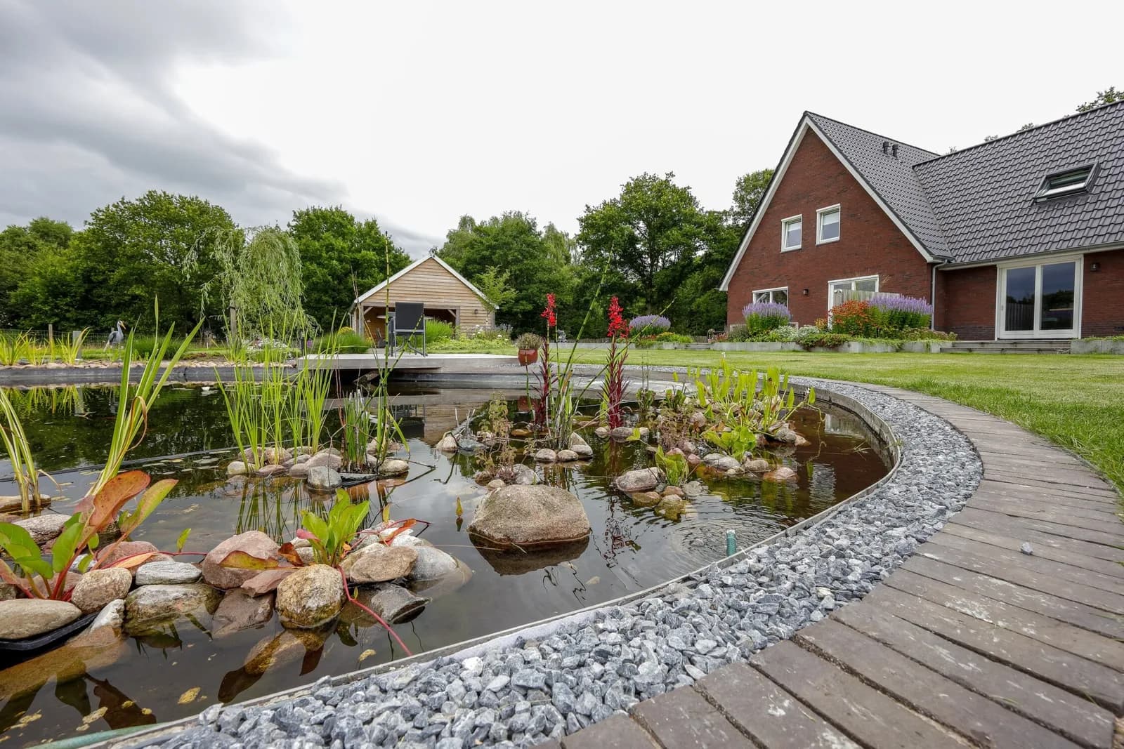 Grote landelijke tuin met royale vijver en hardhouten vlonder.
