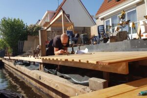 Hovenier van DIM Hovenier legt houten vlonder aan bij water